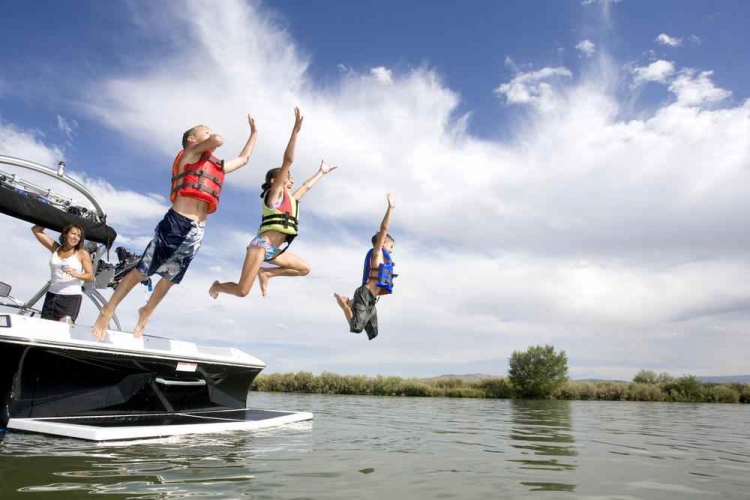 Kids jumping from boat into lake